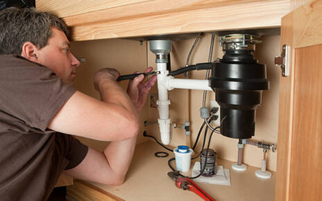 Technician fixing a garbage disposal under kitchen sink in Downtown