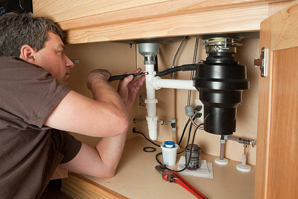 Technician fixing a garbage disposal under kitchen sink in Downtown